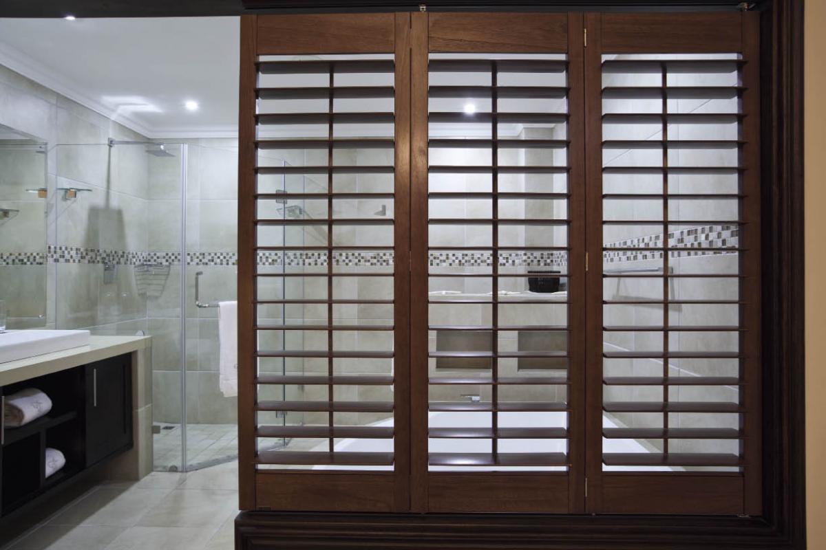 American shutters (011 440 0630)from the Normandy range, stained in old teak, show the versatility of using shutters as a room divider. The shutters were installed on a bi-fold application, which allow them to concertina and stack against the wall when not in use. When shutters are closed, the louvre action still allows for privacy and ventilation.