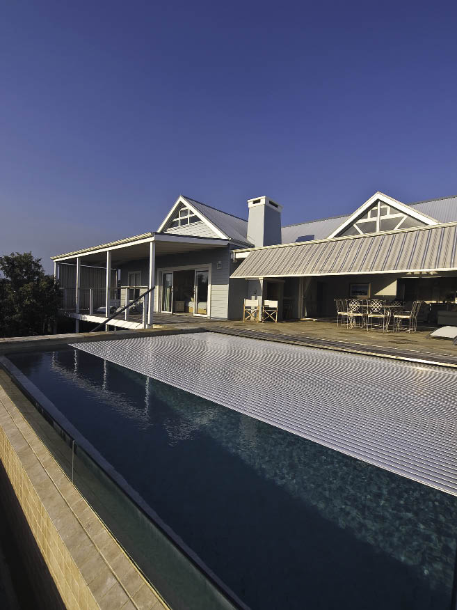 POWERPLASTICS POOL COVERS (021 703 5880)This elegant Sedgefield beach house shows a magnificent finishing touch with the inclusion of the Starline Roldeck automatic pool cover. Manufactured in grey to match the roof, and installed to run across the pool and visually connect with the lines of the awning and house, the Roldeck provides an air of sophistication and completion.